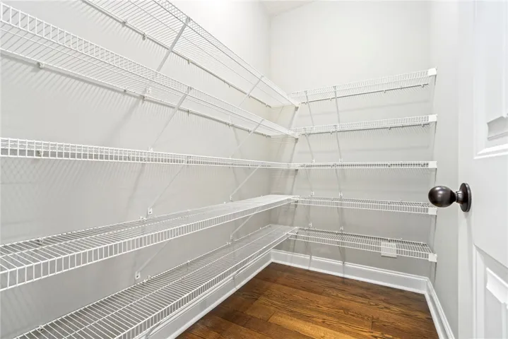 Ample wire shelving lines this functional walk-in pantry featuring rich hardwood flooring.