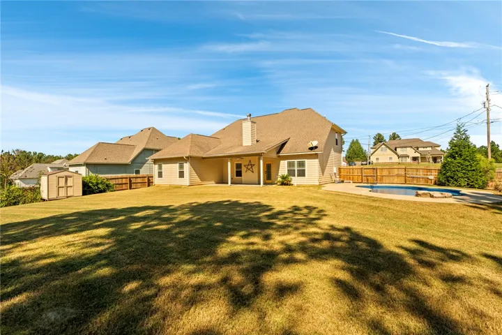 A spacious grassy lawn rolls toward the rear patio and in-ground swimming pool.