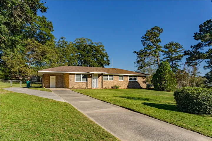 Classic brick architecture anchors a spacious, level green lawn framed by mature trees.