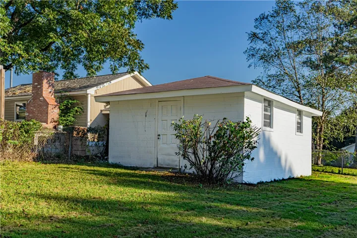 A detached concrete block outbuilding provides excellent storage space within the grassy backyard.