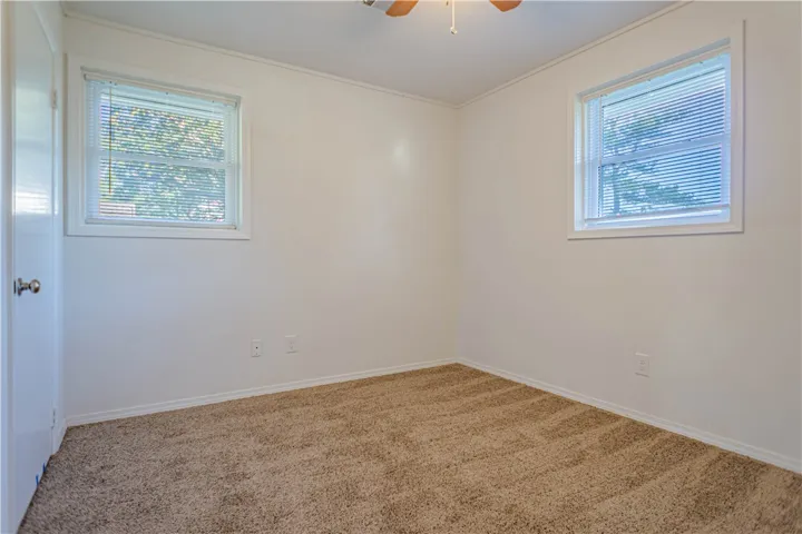 Soft carpeting underfoot and dual windows define this inviting, clean-lined bedroom space.
