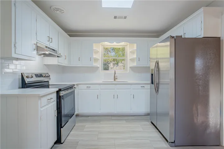 Crisp white cabinetry and modern stainless steel appliances define this functional kitchen workspace.