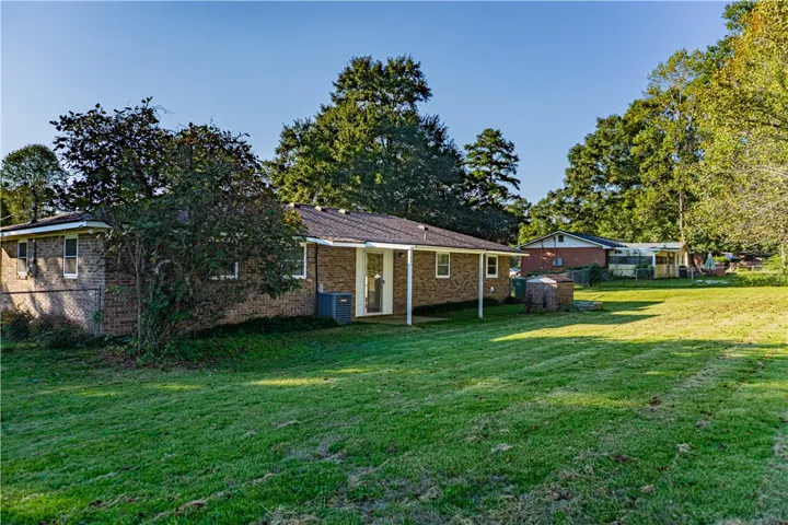 A spacious green lawn borders the classic brick exterior of this single-story home.