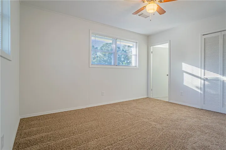Natural light streams through double windows across soft neutral carpeting in this inviting space.