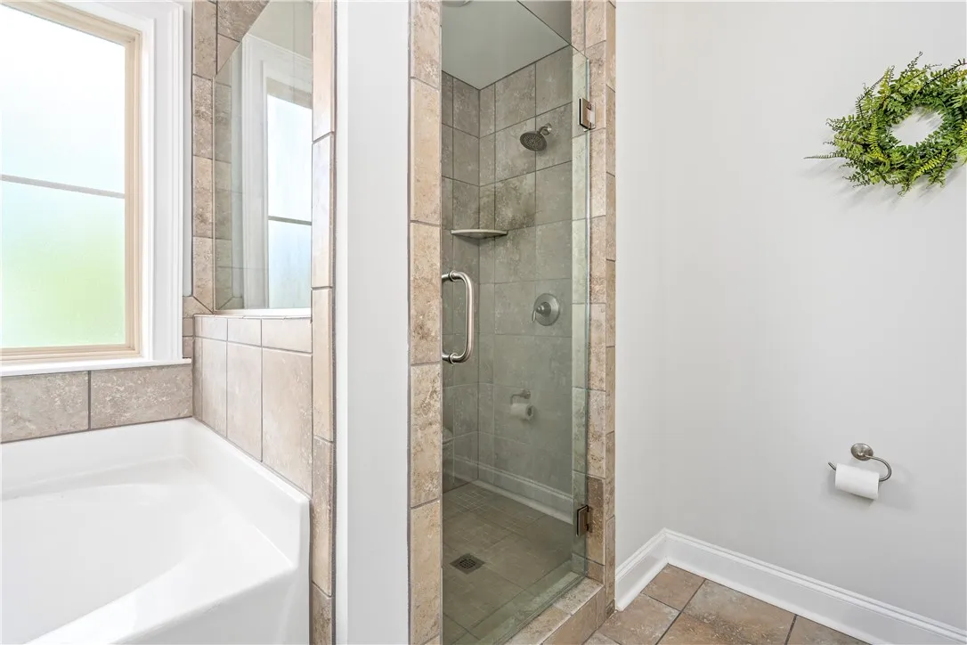 A glass-enclosed walk-in shower stands adjacent to a deep soaking tub.