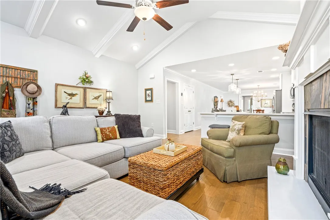 The airy living room with vaulted ceiling and fireplace flows seamlessly to the kitchen and breakfast area.