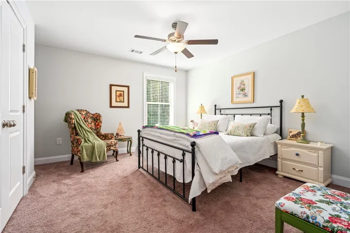 A spacious secondary bedroom features soft wall finishes and a large window facing the back yard.