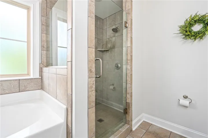 A glass-enclosed walk-in shower stands adjacent to a deep soaking tub.