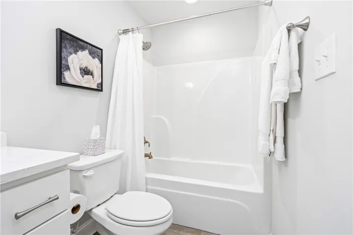 An inviting bathroom features a sleek tub and shower combination with clean white finishes.