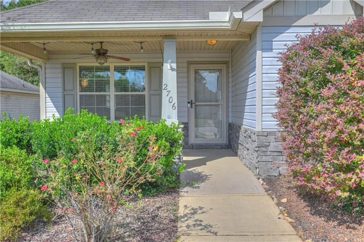 A welcoming front porch with concrete walkway and stone accents greets visitors.