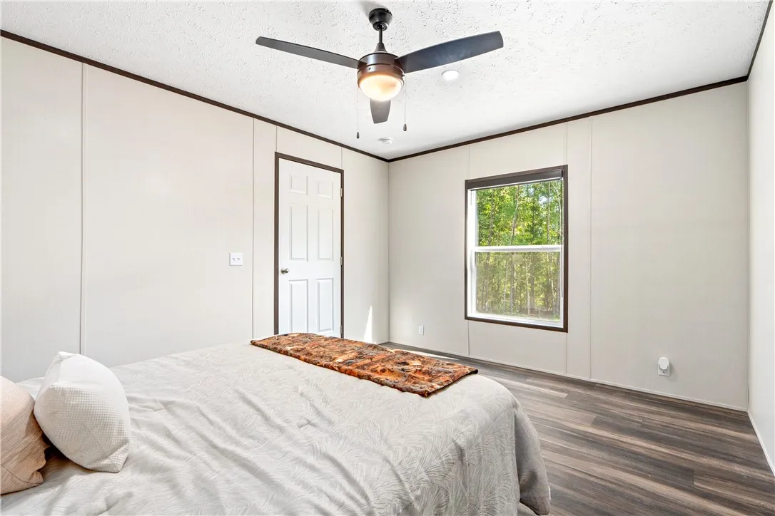 Rich wood-look flooring and dark trim accent this inviting secondary bedroom.