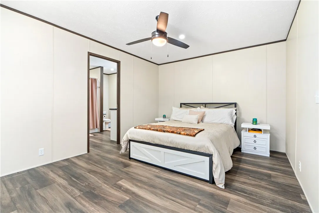 Gleaming wood-look floors anchor this bedroom, offering seamless access to an adjacent private bath.