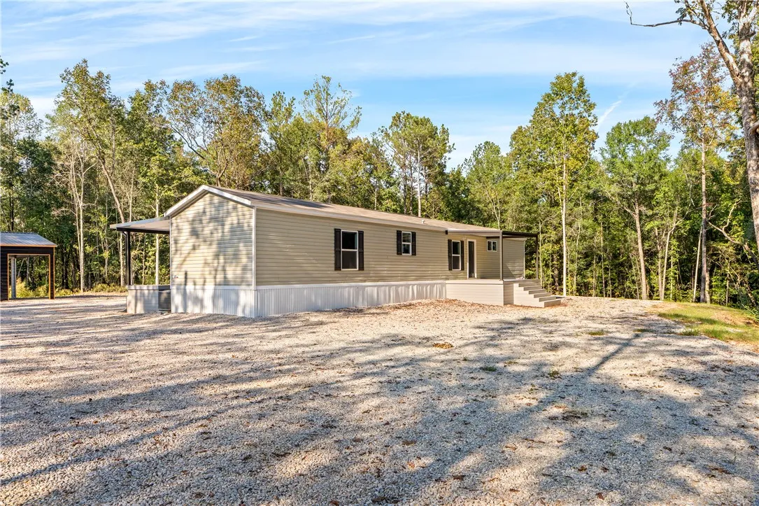 Mature trees frame a private countryside setting complete with an expansive gravel parking area.