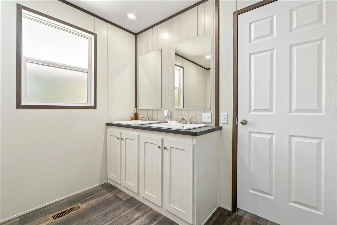 Clean lines and a double vanity define this functional bathroom space with wood-look flooring.