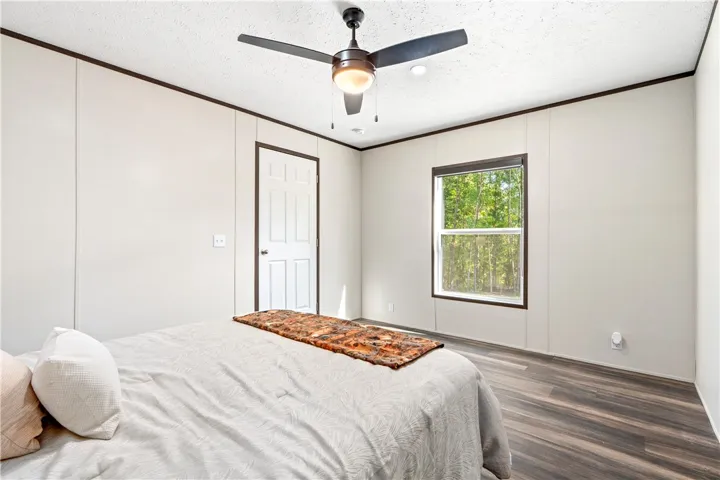 Rich wood-look flooring and dark trim accent this inviting secondary bedroom.