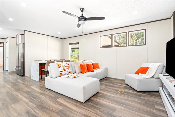Warm wood-toned floors and recessed lighting enhance the open layout of this modern living area.
