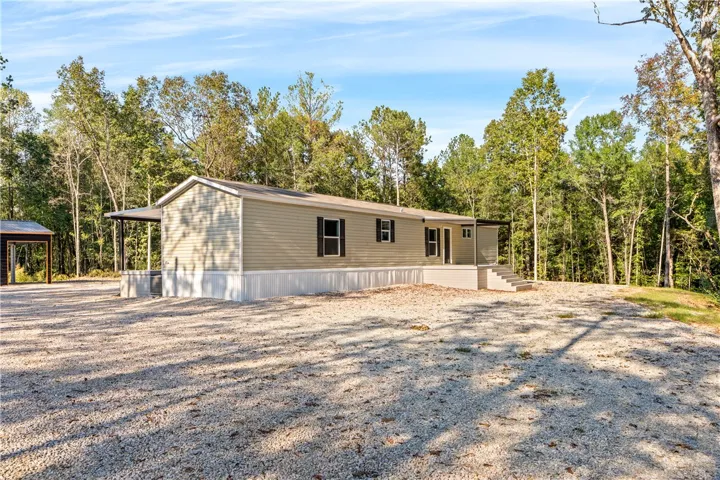 Mature trees frame a private countryside setting complete with an expansive gravel parking area.