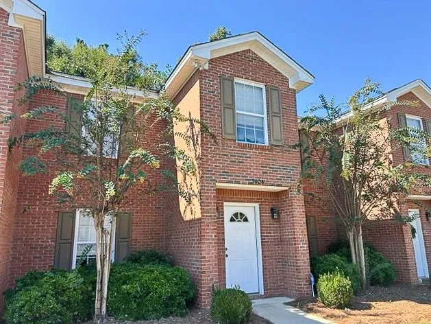 Classic brick architecture defines this multi-level exterior featuring traditional shutters and landscaped entryways.