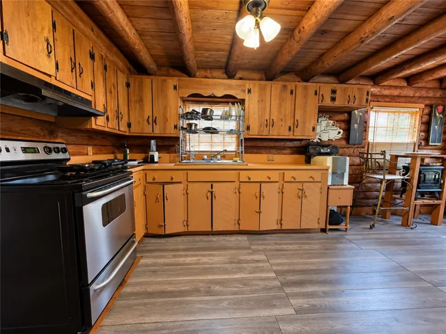 Exposed log construction and beamed ceilings create a warm, inviting rustic kitchen environment.