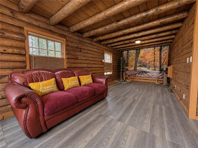 Rich log walls and exposed log ceilings frame this warm, wood-floored living space.