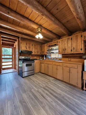 Rustic wood-paneled walls and exposed log ceilings frame this cozy kitchen space.