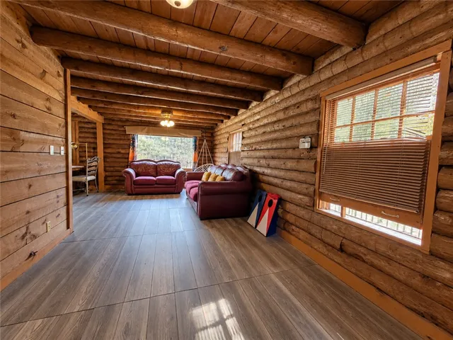 Exposed log walls and robust timber ceiling beams create a warm, rustic cabin atmosphere.