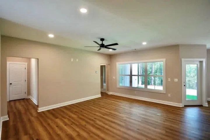 Gleaming wood floors anchor this versatile room illuminated by recessed lights and a wide window.