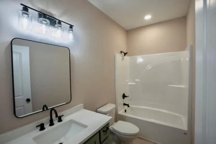 A clean modern bathroom featuring stone counters alongside a combined tub and shower setup.