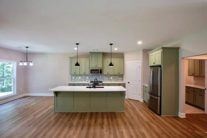 An open kitchen layout showcases wood-look flooring, stone counters, and an expansive center island.