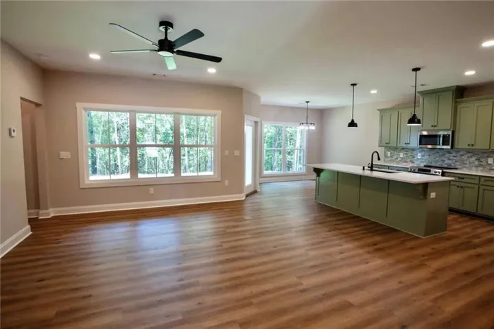 Rich wood floors sweep through this airy, open-concept layout connecting the kitchen and living areas.