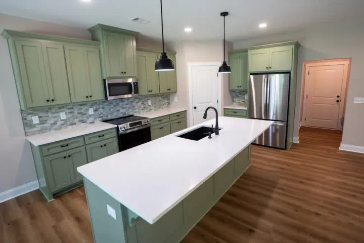 An open kitchen centers on a large island under recessed lighting and smooth wood-textured flooring.