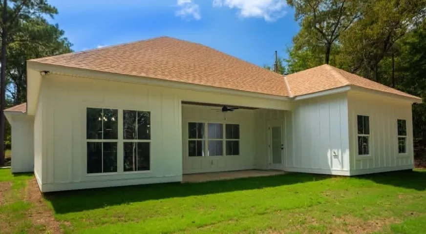 A deep covered porch provides a sheltered transition between the modern board-and-batten exterior and green lawn.