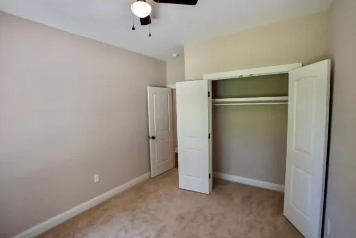 A quiet bedroom features plush carpeting and a spacious built-in closet with double doors.
