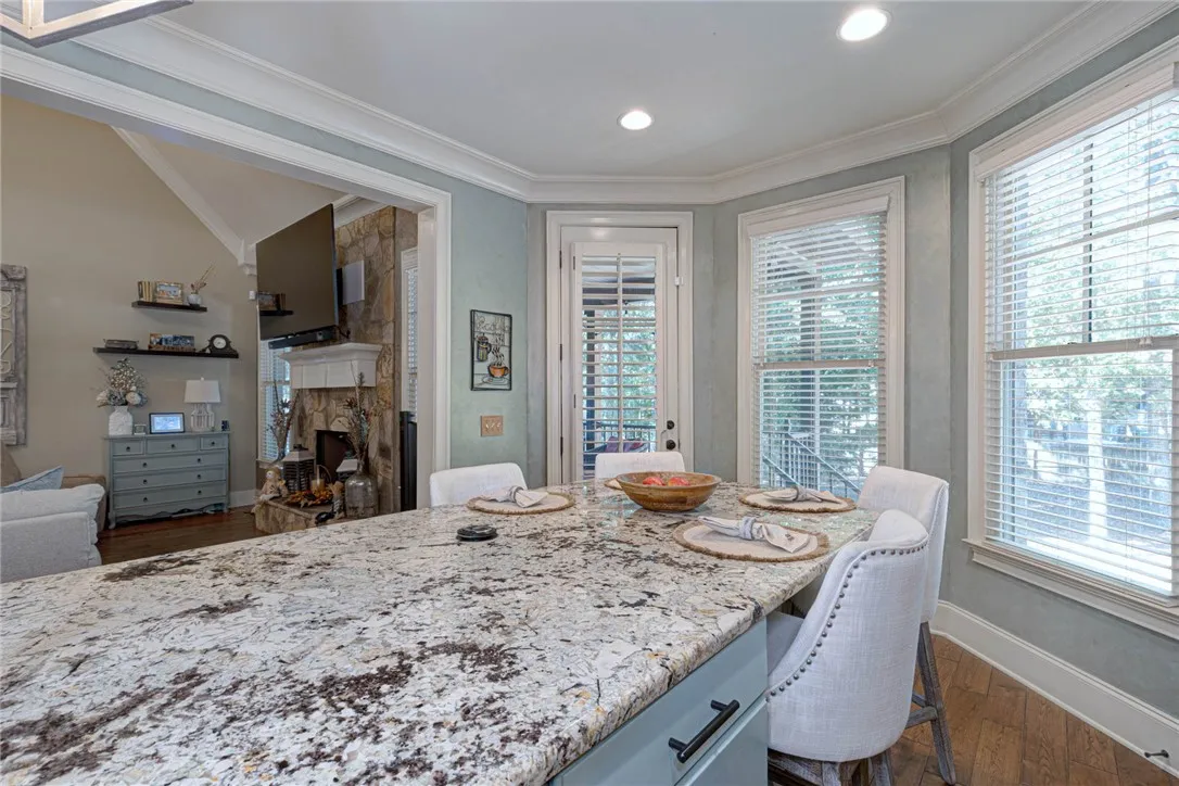 Stone countertops and detailed crown molding enhance this light-filled dining and kitchen area.