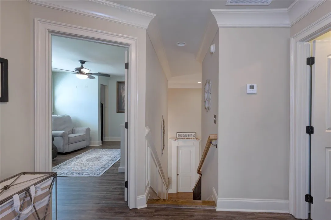 Crisp crown molding and durable luxury flooring anchor this functional, multi-level hallway space.