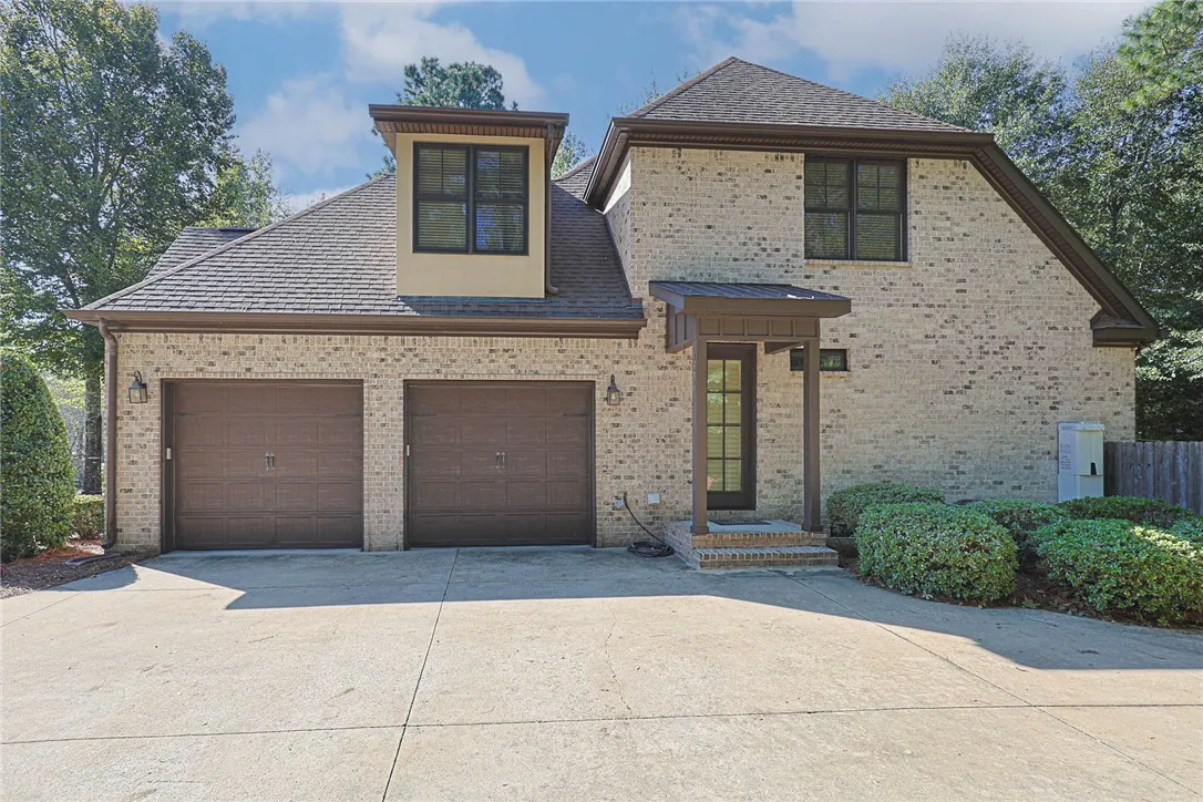 A classic brick exterior presents structured architectural lines, dormer windows, and a paved multi-car driveway.
