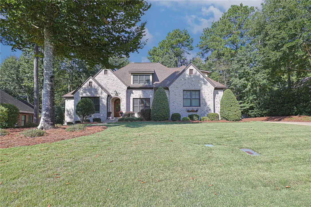 Mature trees frame a classic stone veneer facade fronted by a wide, manicured lawn.