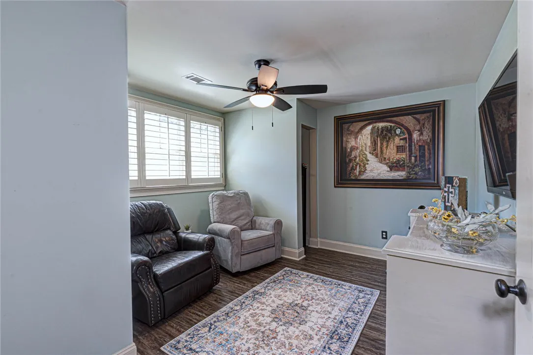 Rich wood-look flooring and custom shutters elevate this versatile living space.