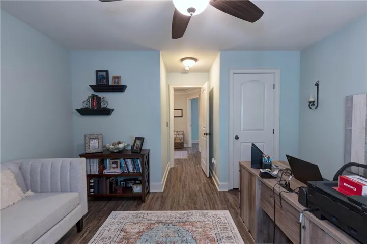 A comfortable home office space features durable wood flooring and an open doorway leading to the hallway.