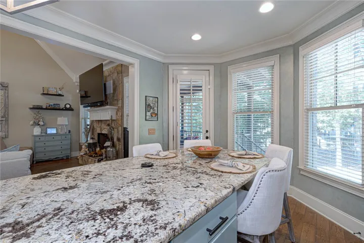 Stone countertops and detailed crown molding enhance this light-filled dining and kitchen area.