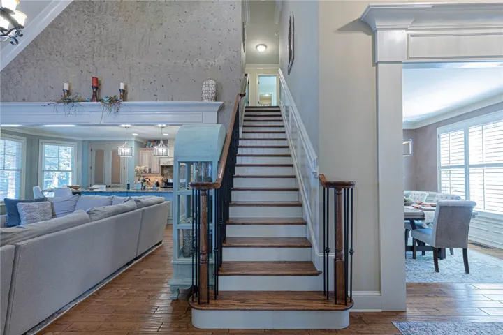 Rich hardwood flooring complements a grand staircase set within an airy, multi-level layout.
