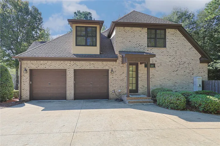 A classic brick exterior presents structured architectural lines, dormer windows, and a paved multi-car driveway.