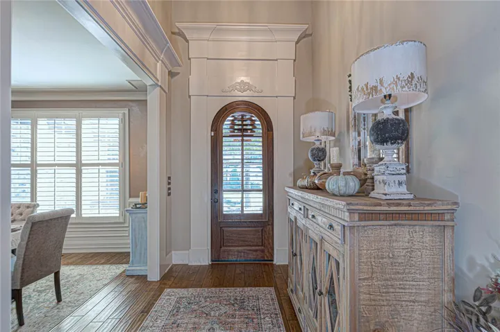 An arched entry door under towering ceilings framed by elaborate millwork creates an imposing welcome.