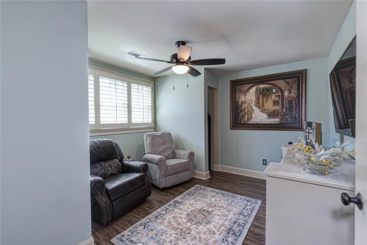 Rich wood-look flooring and custom shutters elevate this versatile living space.