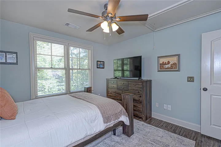 Large multi-pane windows bring natural light and views of mature trees into this cozy bedroom.