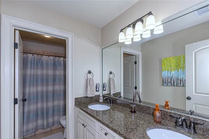 Polished granite counters and a dual vanity define this functional second-floor bathroom layout.