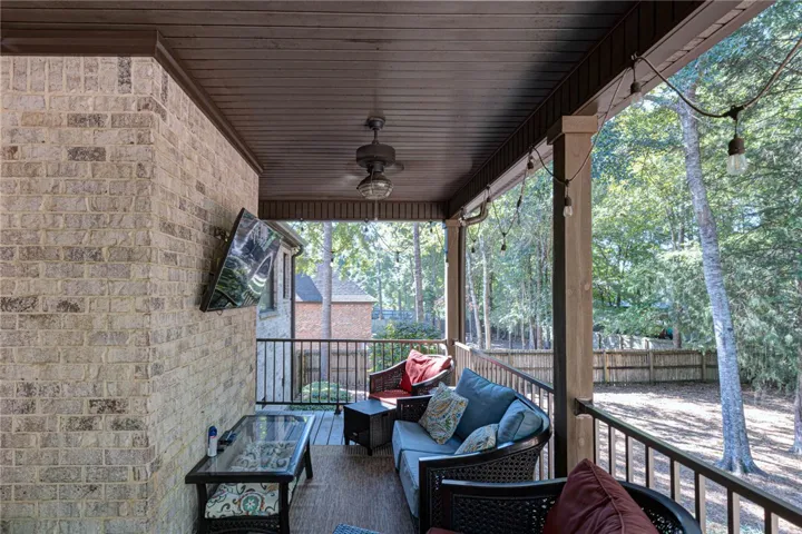 A covered back porch features a beadboard ceiling and views of the wooded backyard.