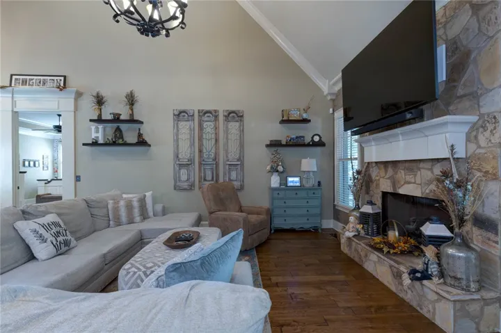 A stone fireplace anchors the living space under vaulted ceilings and handsome hardwood flooring.
