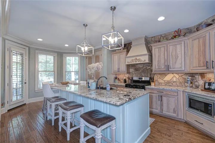 Warm wood cabinetry and stone accents complement a central island in this culinary space.