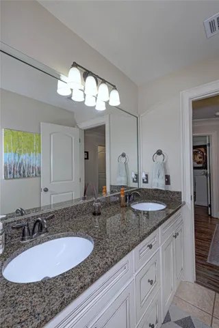 A classic vanity featuring granite counters and two under-mount sinks serves this bathroom space.